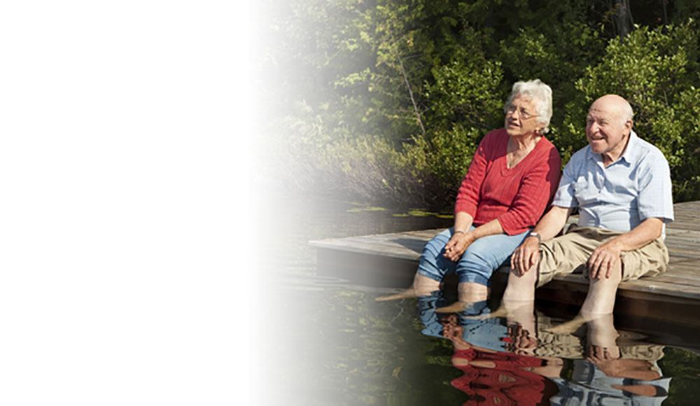Elderly couple dipping feet in lake